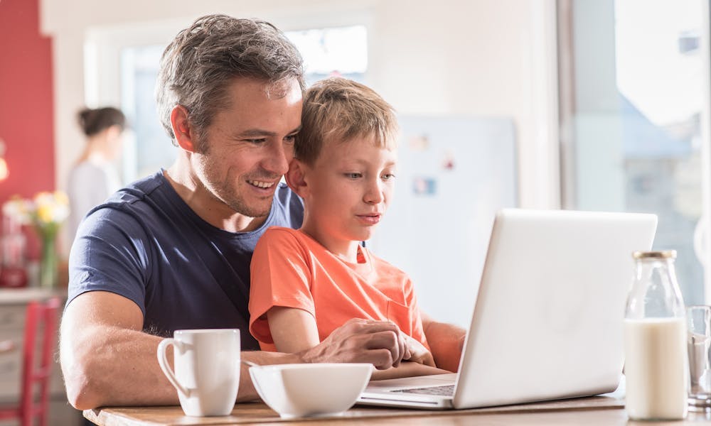 Father and son using a computer during breakfast