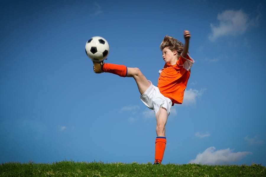 Young girl kicking a soccer ball in the air