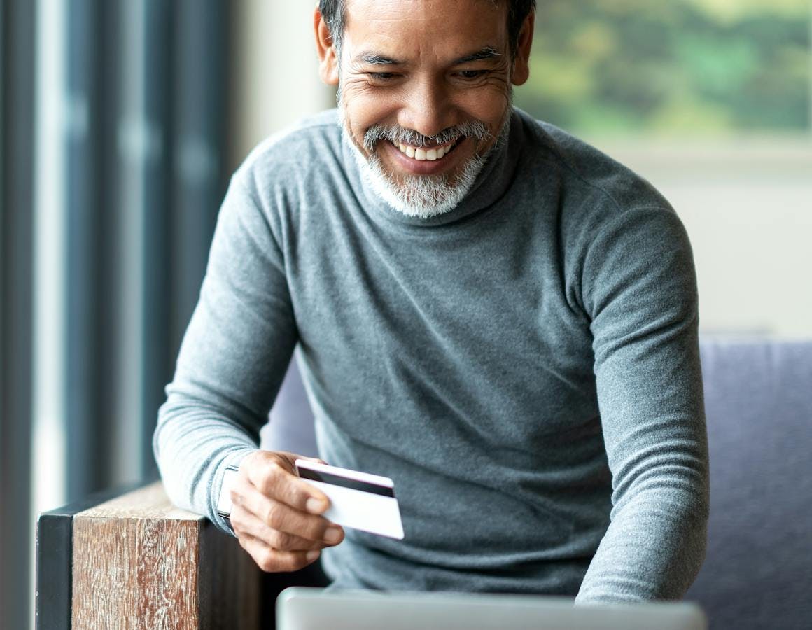 man smiling holding credit card