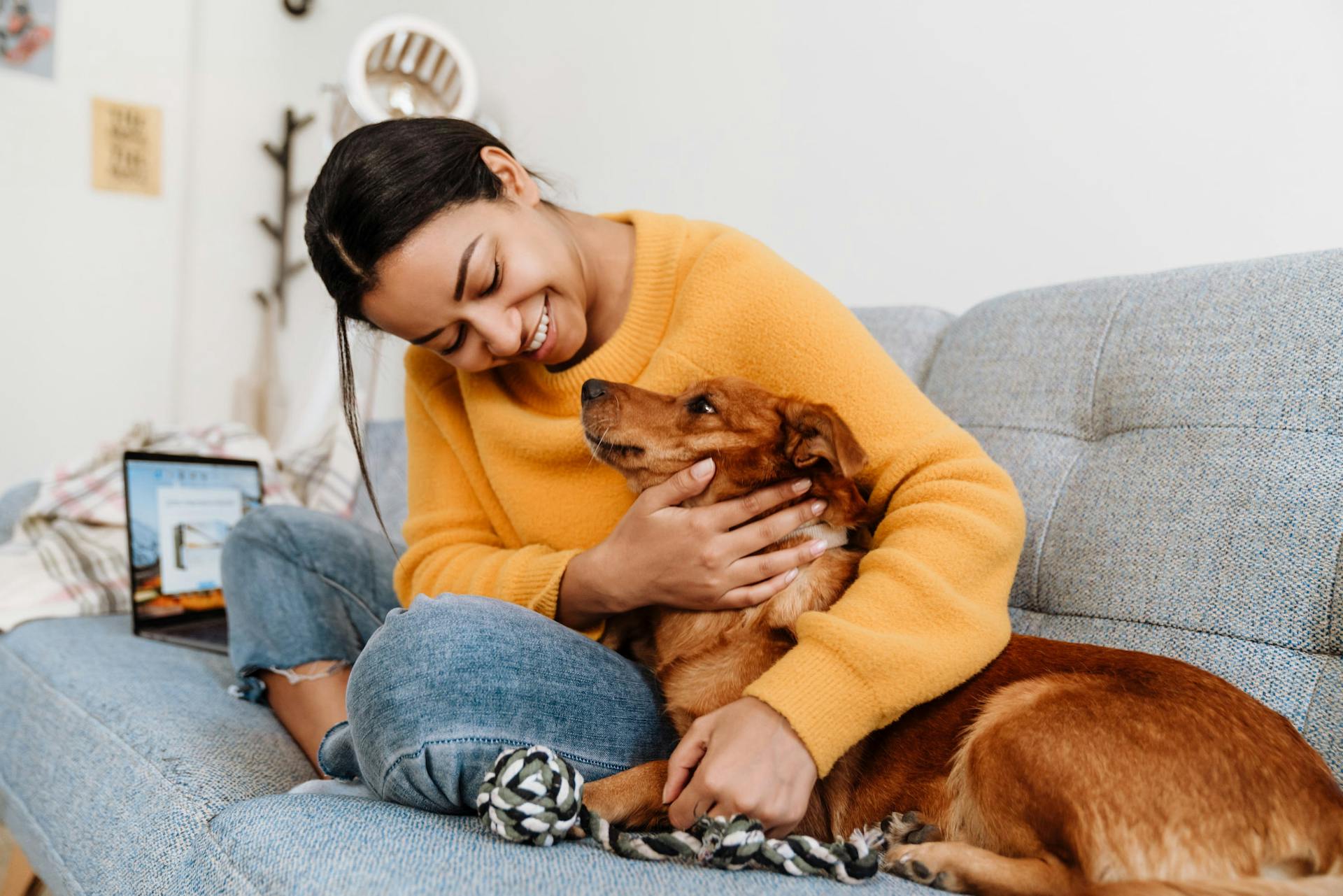 Woman snuggling dog on couch