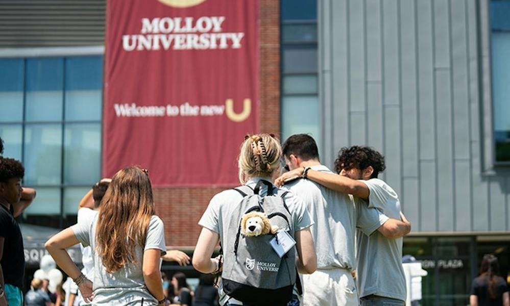 Students gathered in front of a Molloy University building 