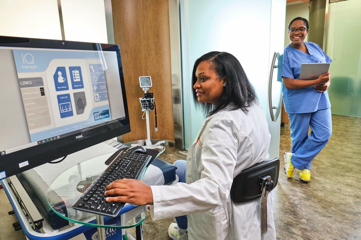 Two medical professionals working at a computer and smiling