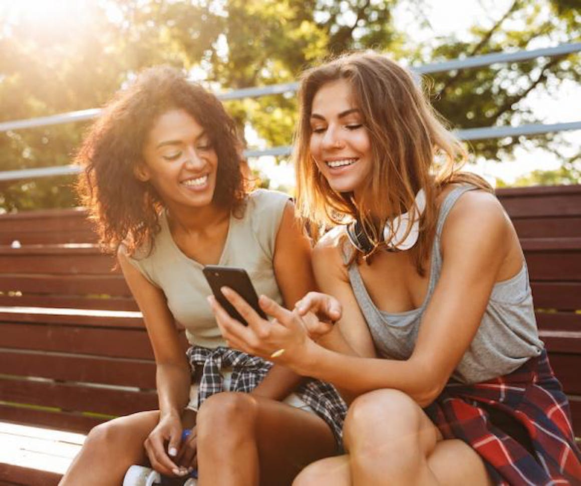Two women looking at a phone and smiling
