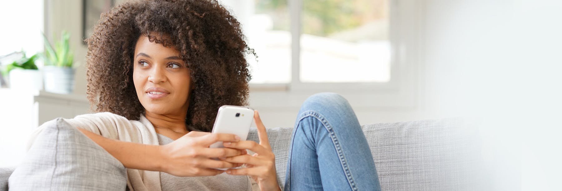 A woman on her mobile device sitting on a couch 