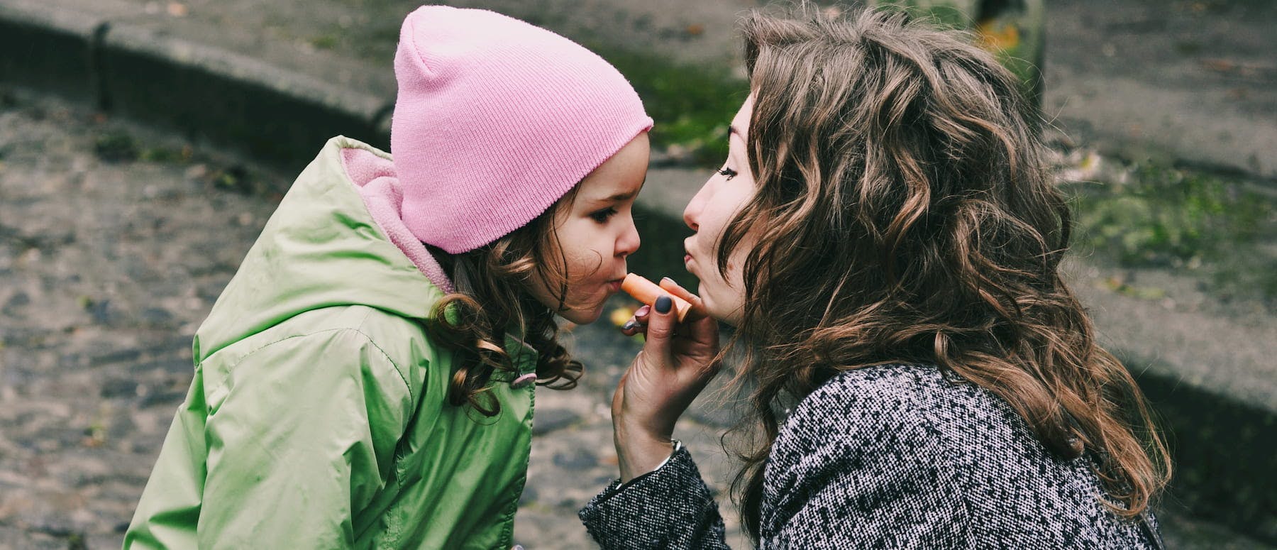 A mom applying lip balm to her daughter