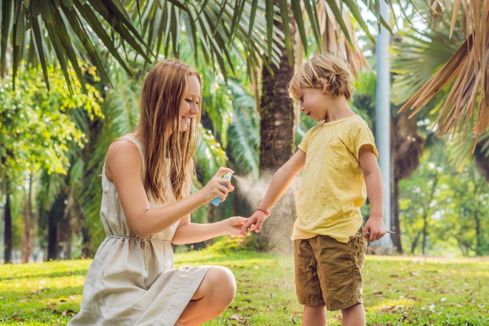Mom spraying insect repellant on her son 