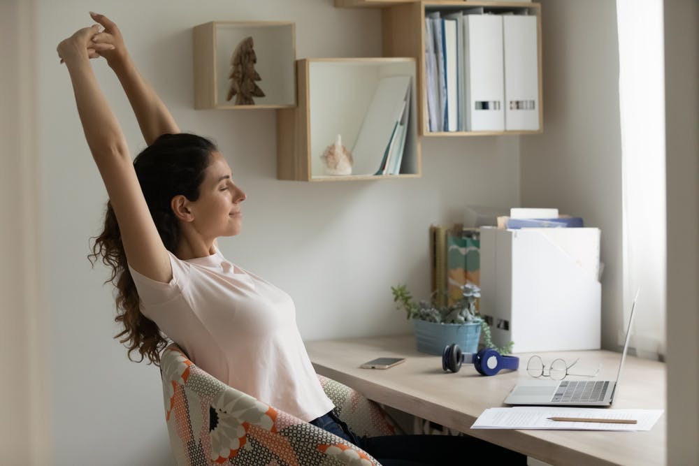 A woman stretching her arms sitting at her desk